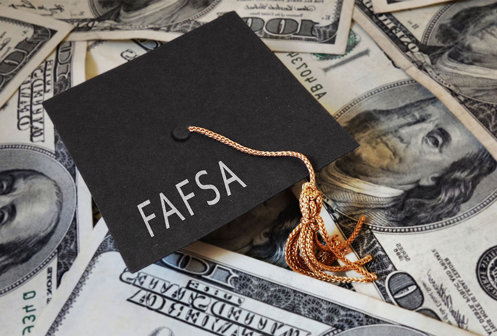 Graduation cap adorned with the word "FAFSA" sits on top of a pile of money
