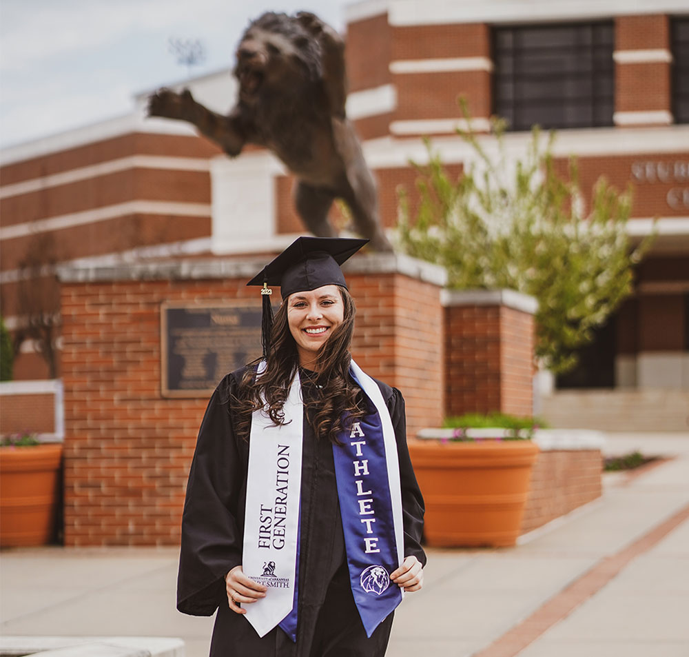 First-Generation and student-athlete, Hannah Boyett poses on graduation day, May 2023 in front of the Numa statue at the Stubblefield Center.